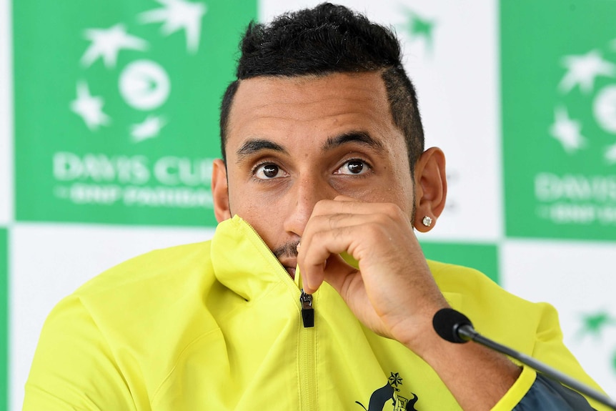 Nick Kyrgios covers his mouth with his shirt