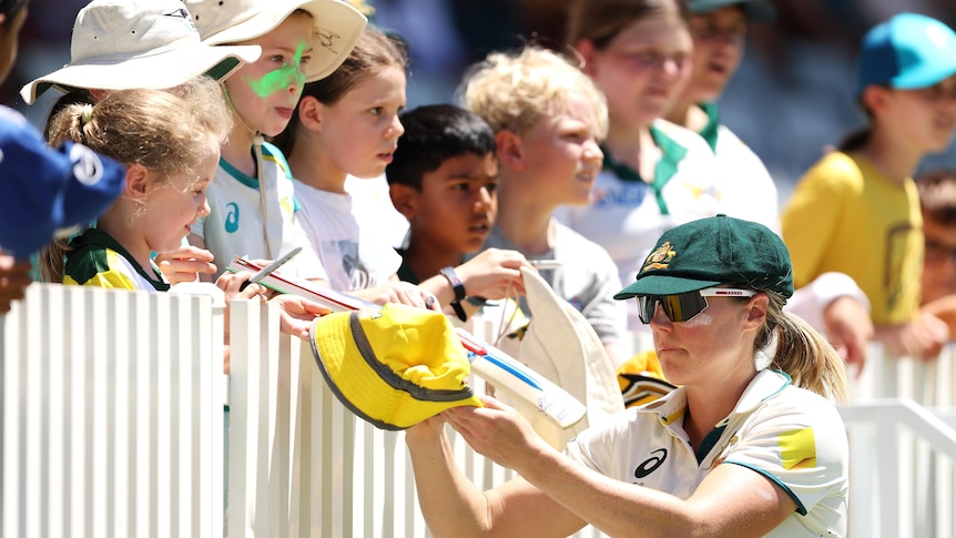 Test cricketer Ellyse Perry signing hats and bats of kids attending a Test match