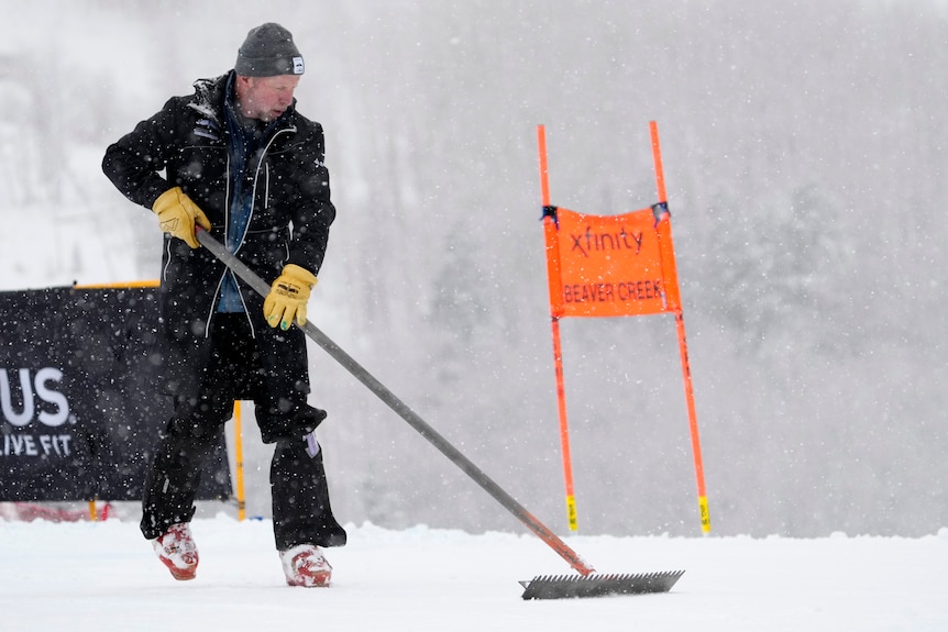 Man uses a snow rake to clear a course 
