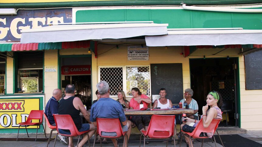 Nine locals gather around a pub table in Mount Morgan drinking beers and sharing stories about cyclone Marcia