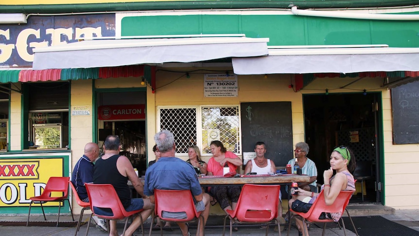 Nine locals gather around a pub table in Mount Morgan drinking beers and sharing stories about cyclone Marcia