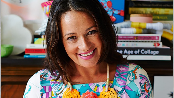 A woman wearing a bright-coloured dress looks at the camera.