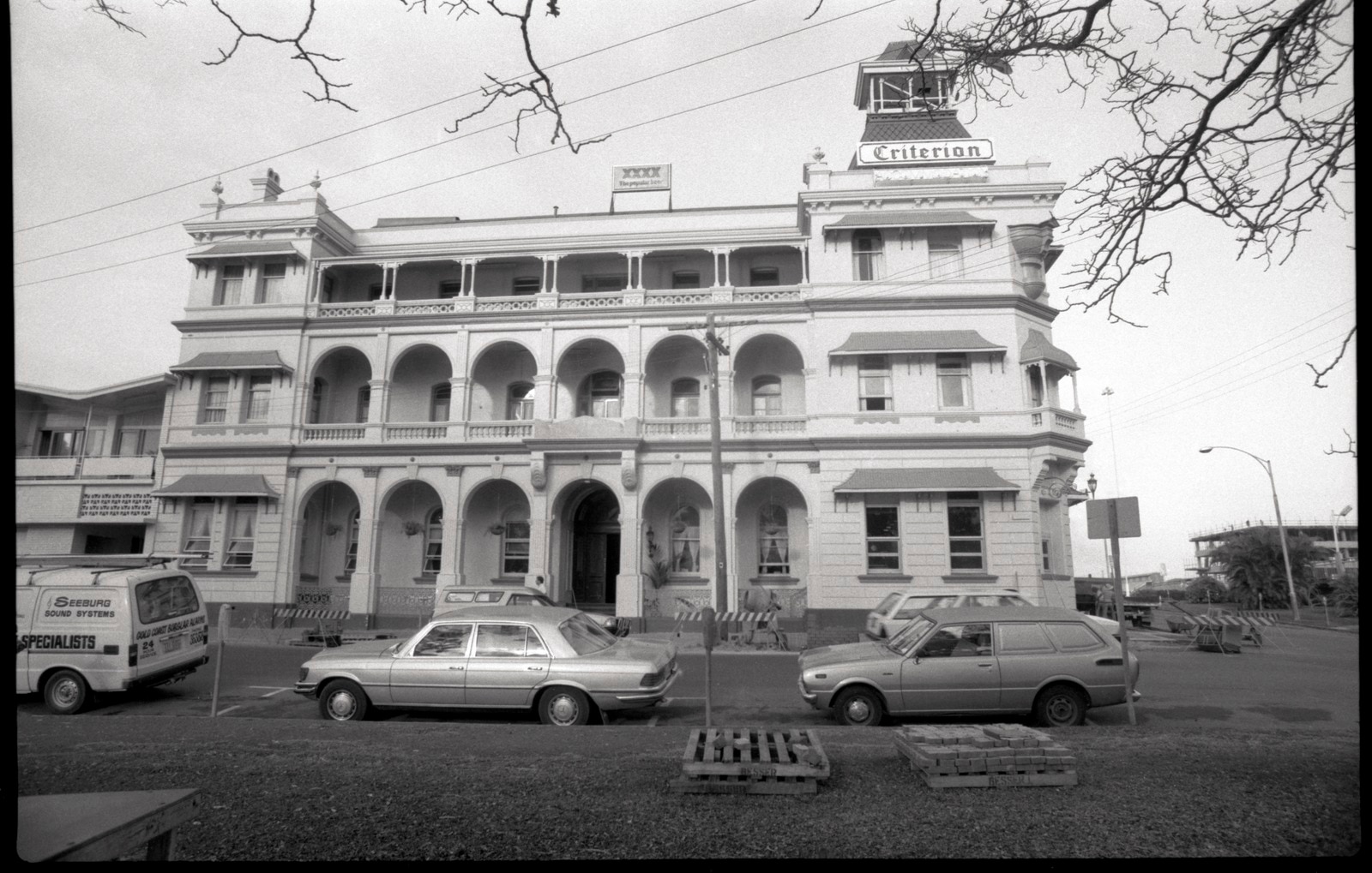 Black and white three storey hotel with verandah, windows, cars on road