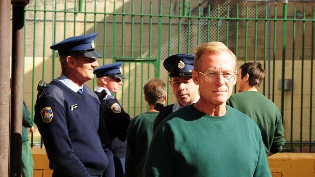 Richard Roxburgh surrounded by police officers.