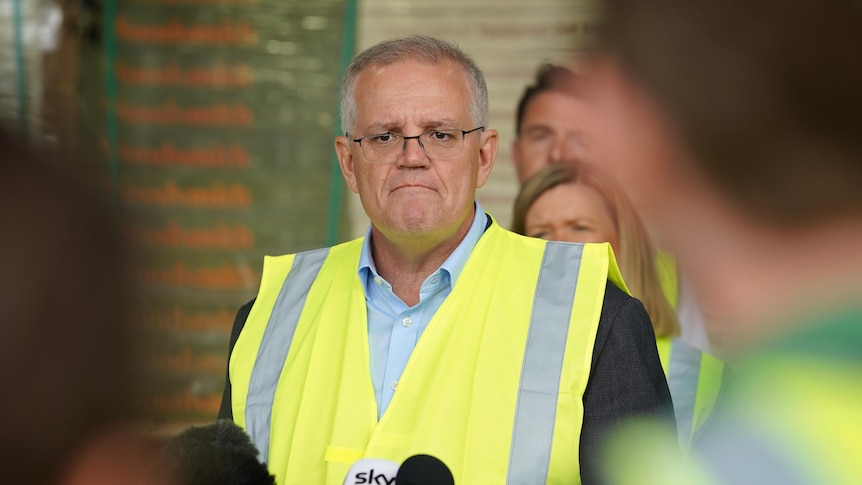 Scott Morrison wearing a yellow high vis vest in front of microphones at a press conference