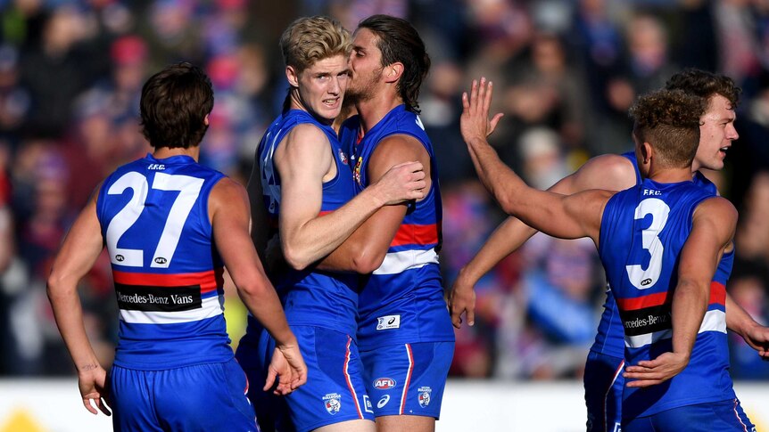 Tim English is hugged by Tom Boyd after kicking a goal for the Bulldogs against the Suns.