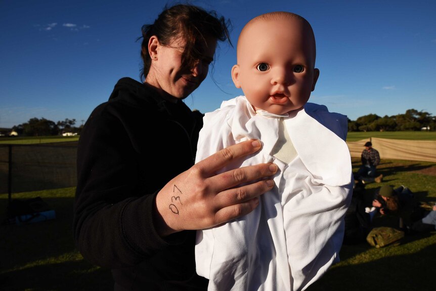 A numbered evacuee with her baby awaiting transport