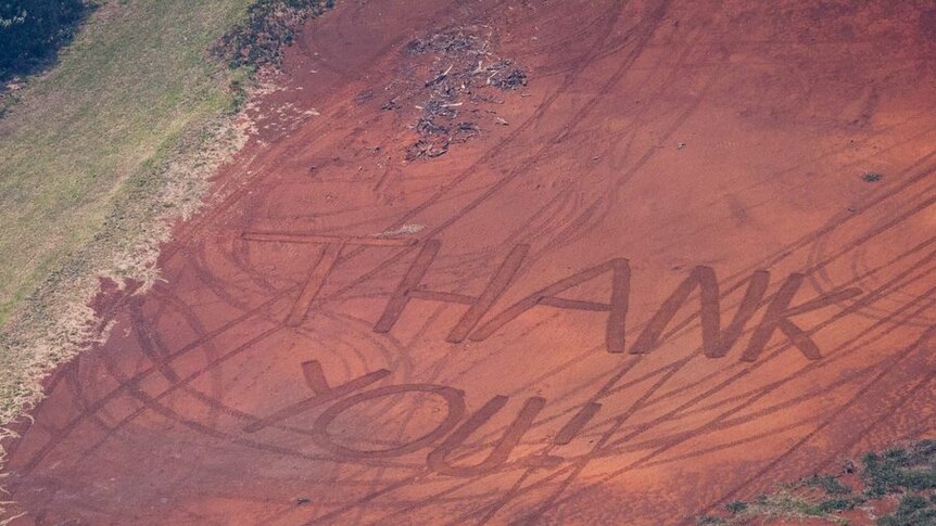 An aerial shot shows Thank You written near a patch of blackened earth during bushfires.