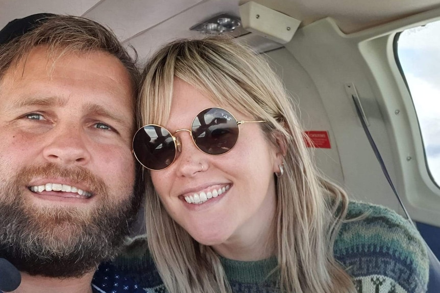 A man and a woman pose for a selfie on board a plane