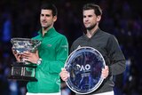 The two finalists in the Australian Open stand next to each other, one holding the winner's trophy.