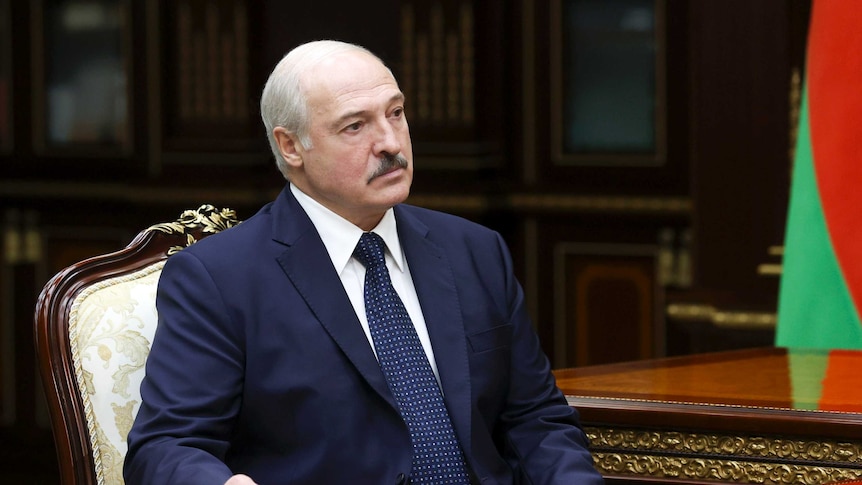 Belarusian President Alexander Lukashenko wears a suit and sits at a table.