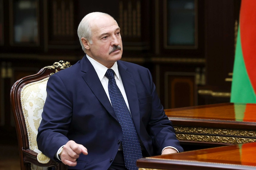 Belarusian President Alexander Lukashenko wears a suit and sits at a table.