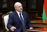 Belarusian President Alexander Lukashenko wears a suit and sits at a table.