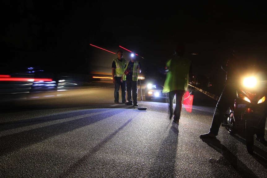 A group of men repairing a road at night.