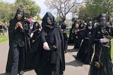 Climate protesters dressed in black robes with white face paint in Fitzroy.