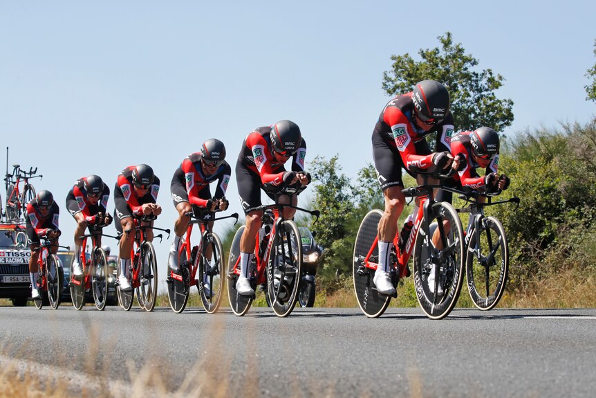 Team BMC cycle in a line on their time trial bikes.