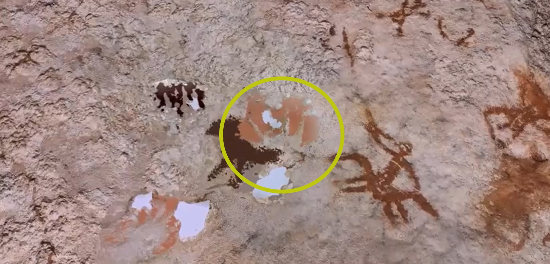 Uma parede de caverna com seções destacadas para mostrar uma leve impressão de mão.