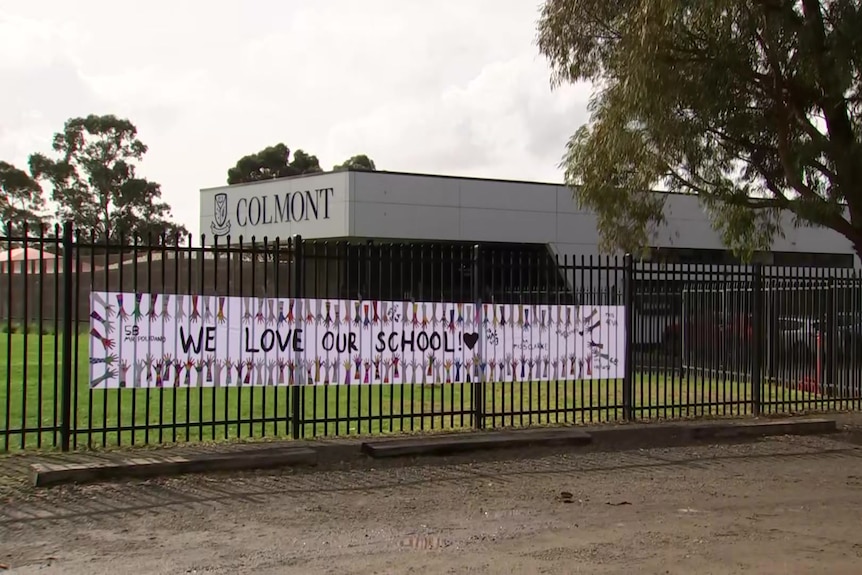 a sign on the fence of the school says "we love our school"