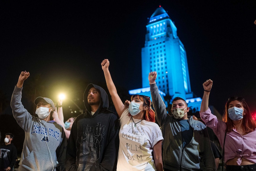 A group of demonstrators raise their fists in protest.