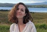 A woman smiling in front of a lake