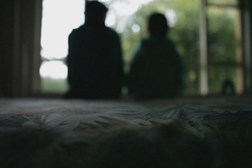 blurred image of children sitting on bed near window