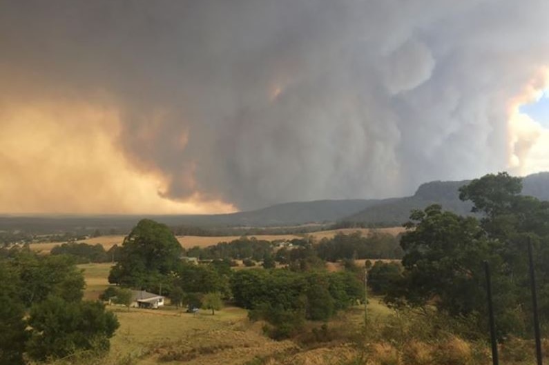 A rural scene with a large plume of smoke on the horizon.