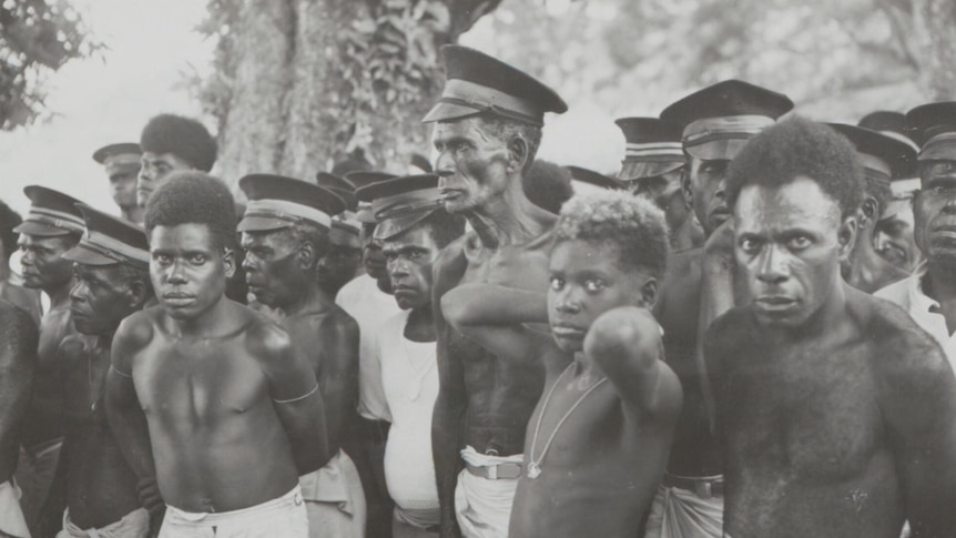 a black and white photo showing a group of shirtless men in Bougainville