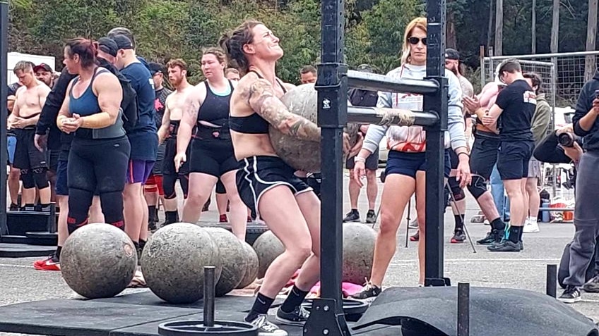 Strength athlete Josie Hamor lifting an Atlas stone over a bar