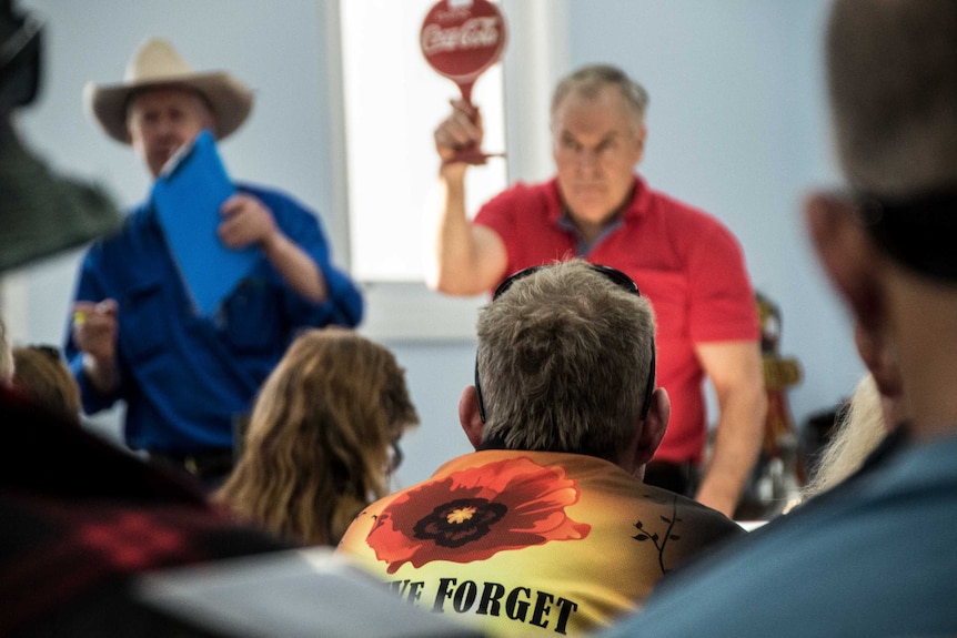 A man wearing a t-shirt saying Lest We Forget at an auction for military memorabilia.
