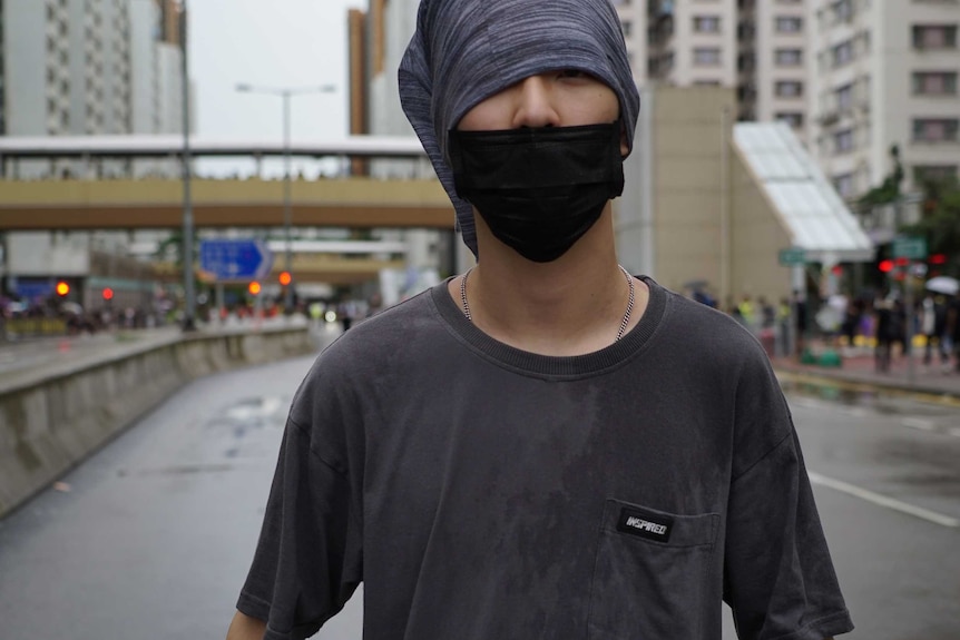A young man with a face mask on standing on a Hong Kong street