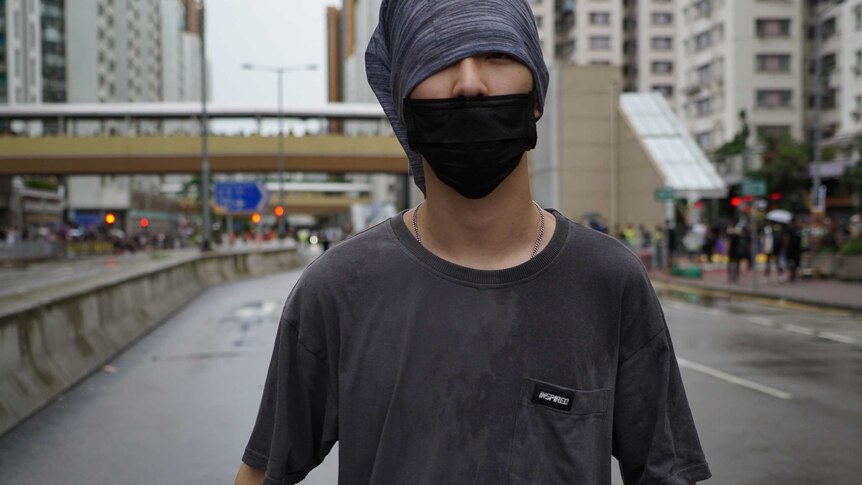 A young man with a face mask on standing on a Hong Kong street