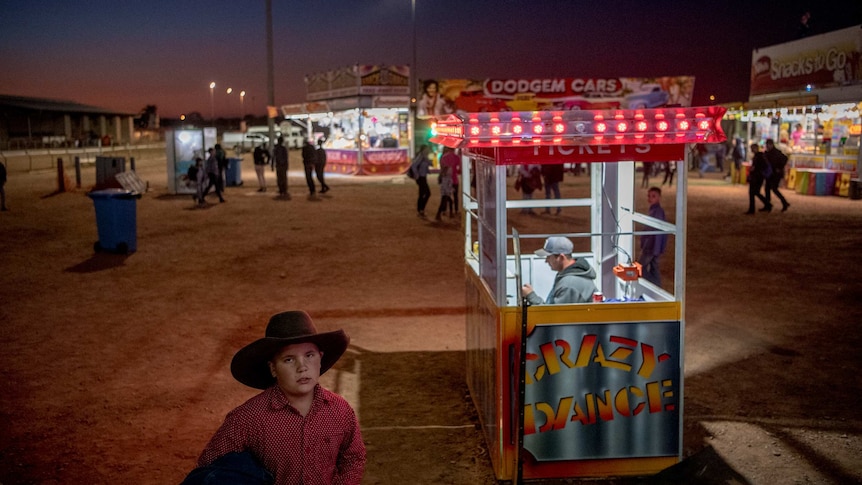 A night shot of a young boy in sideshow alley.