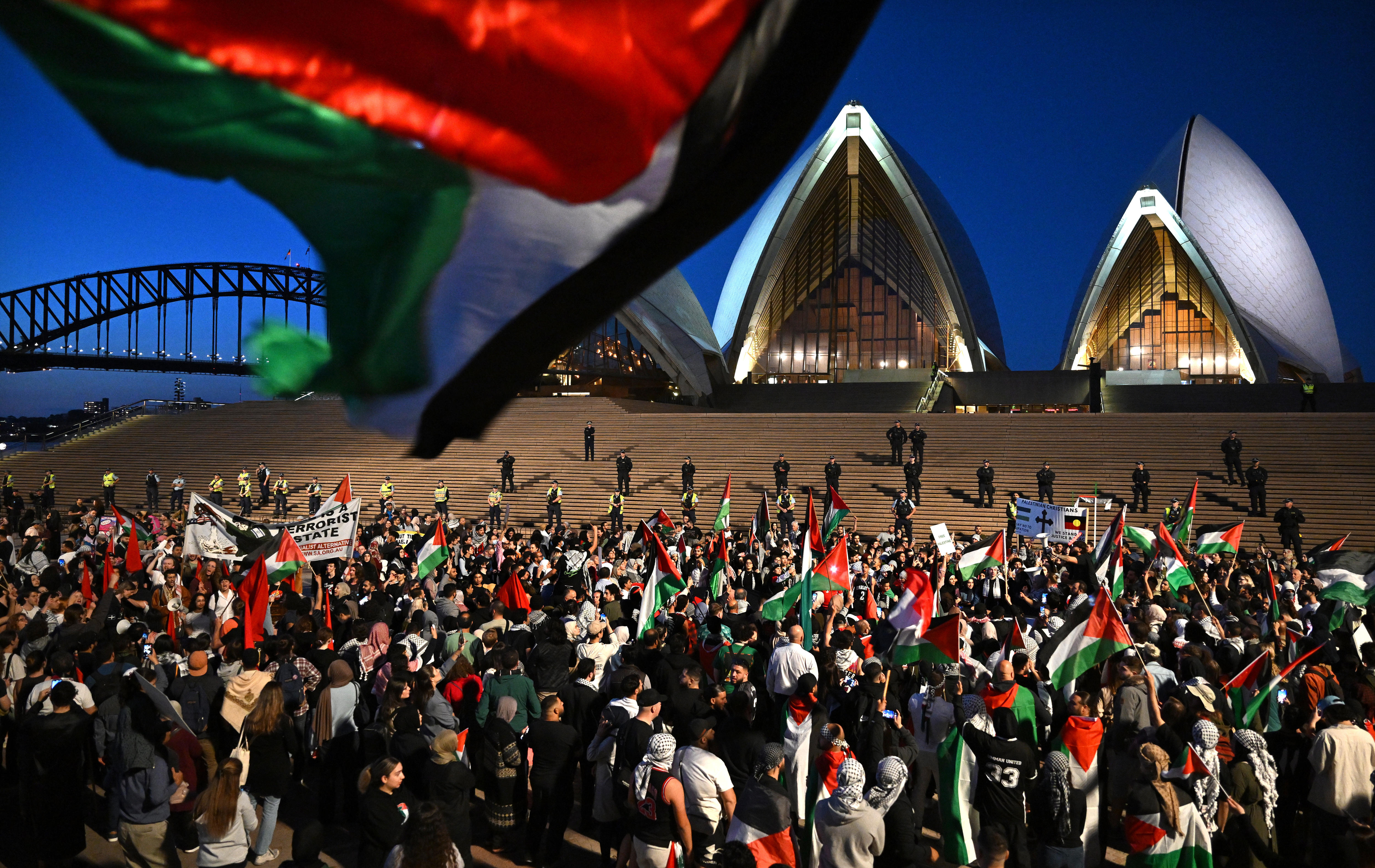 Palestinian flag being waved in front of crowds gathered outside the Opera House