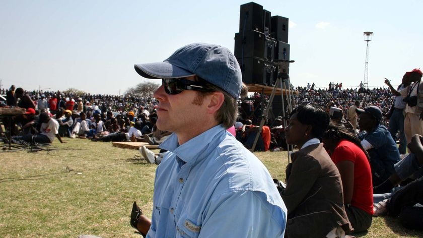 ABC Africa correspondent Andrew Geoghegan sits with thousands