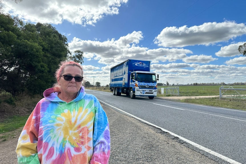 woman standing near rural road with truck in background