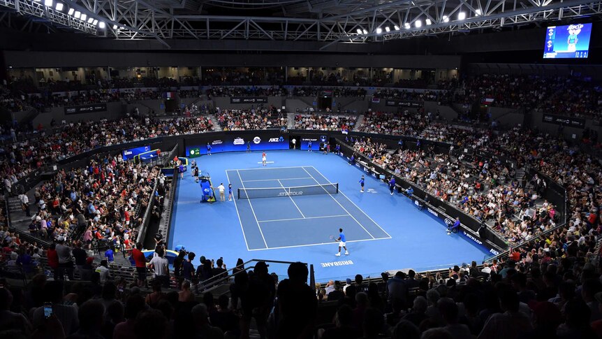 A general shot of a blue tennis court surrounded by stadium full of people