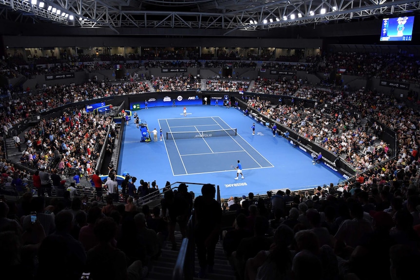 A general shot of a blue tennis court surrounded by stadium full of people