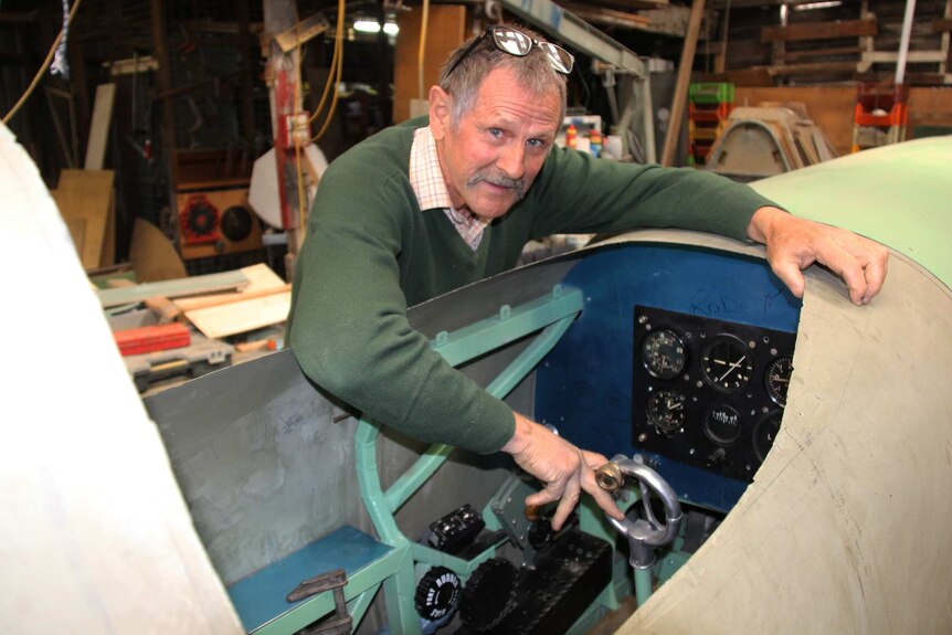 Rod McNeill leans over the cockpit which includes original dials from a museum in the UK.