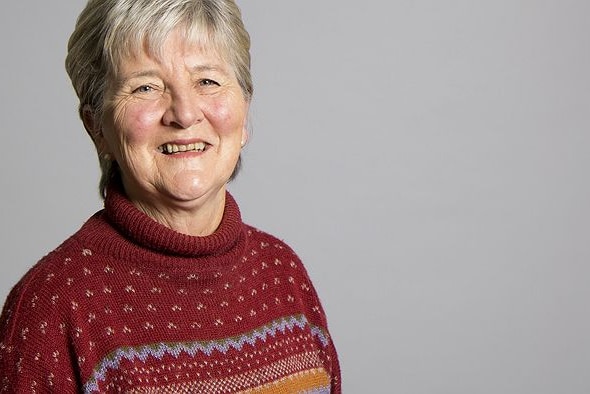 Lynette Silver smiles at the camera against a grey background.