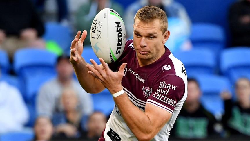 A Manly Sea Eagles NRL player catches the ball with both hands.