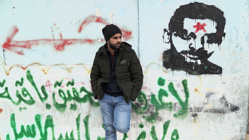 Fadi Zebar stands in front of a mural in Israel, December 2018.