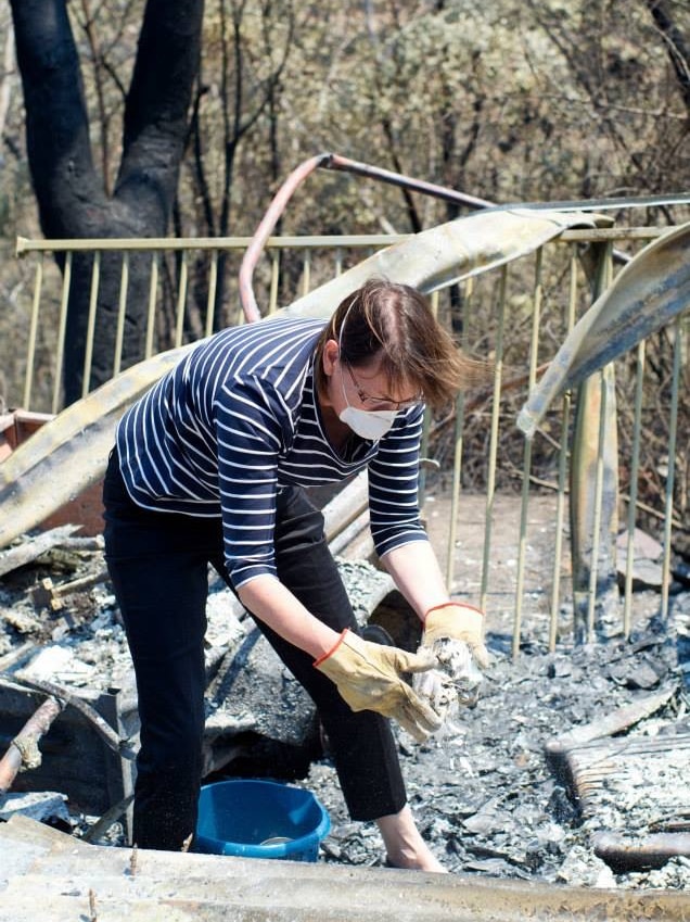 A woman kneels over the rubble left behind after the Blue Mountains bushfires in 2013.