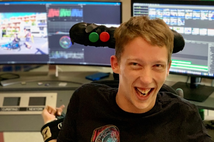 A smiling man sitting in front of computer screens