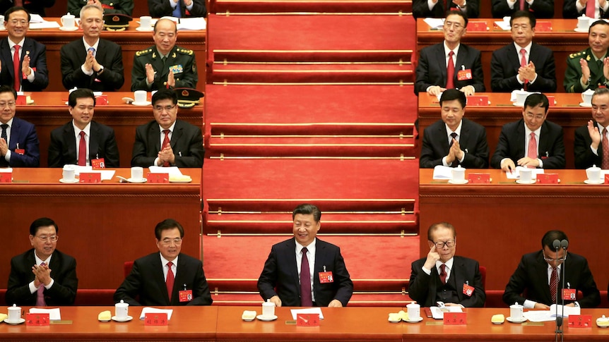 Chinese President Xi Jinping speaks surrounded by members of the Communist Party.