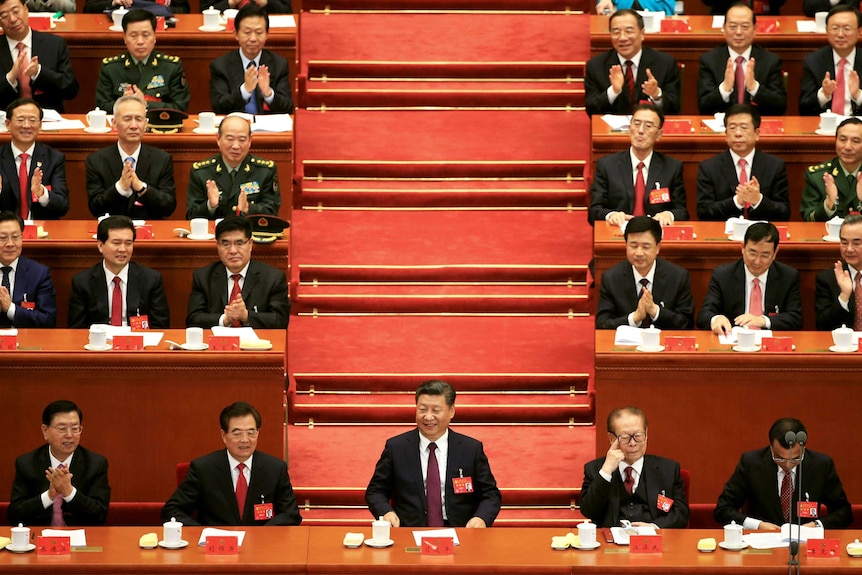 Chinese President Xi Jinping speaks surrounded by members of the Communist Party.