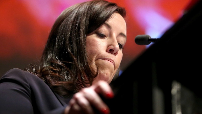 woman at the podium with her lips pursed