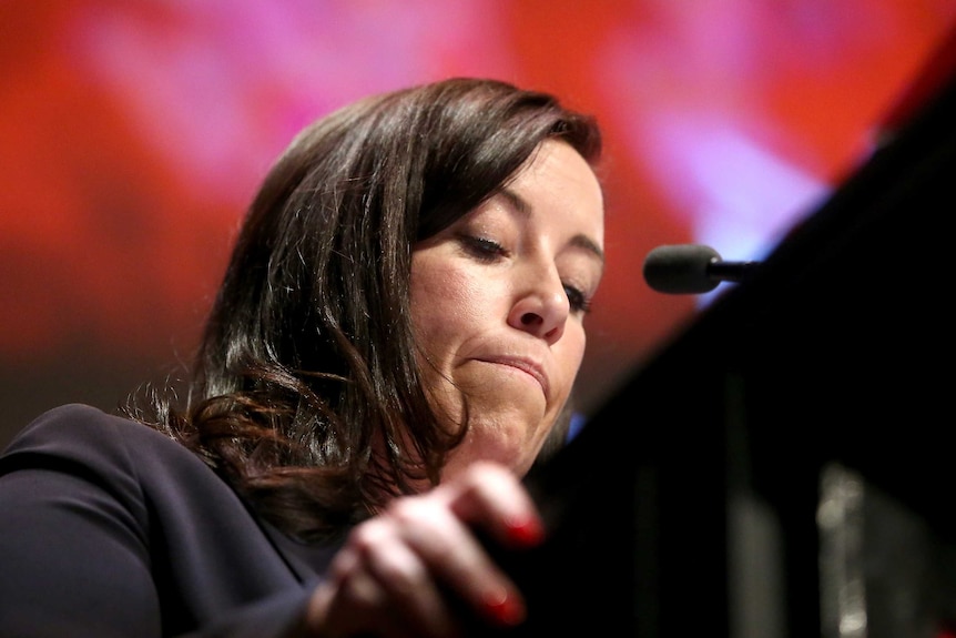 woman at the podium with her lips pursed