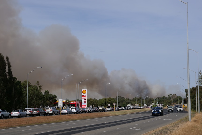 Line of traffic on a highway. Smoke from a bushfire is in the background.