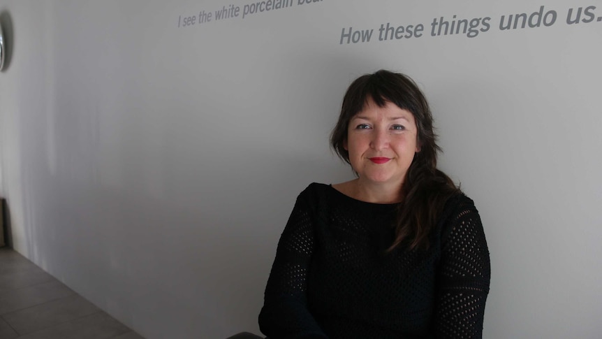 Pippa Dickson chairwoman of Design Tasmania sits in front of a wall.