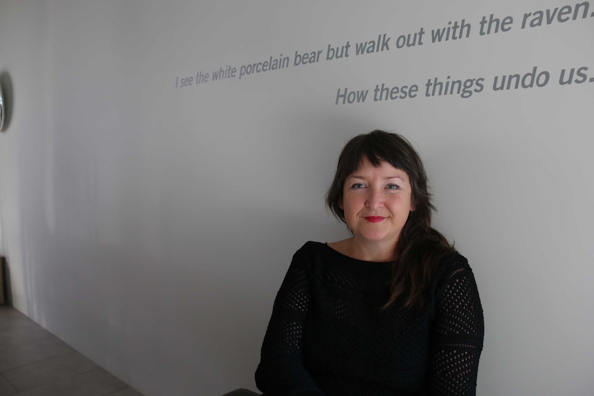 Pippa Dickson chairwoman of Design Tasmania sits in front of a wall.